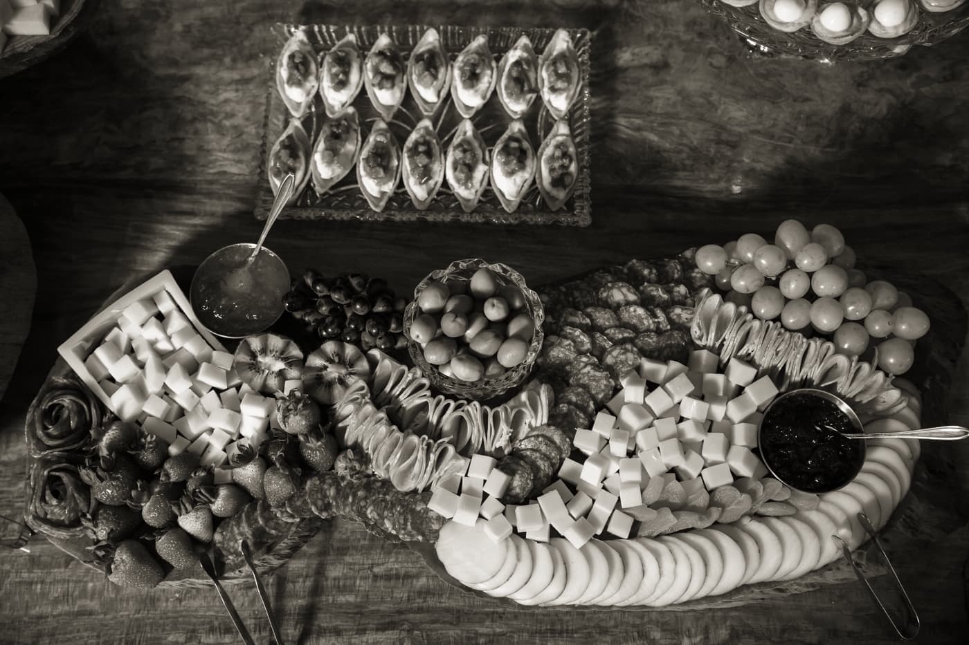 A loaded charcuterie board of cheeses, cured meats and grapes on a wooden table