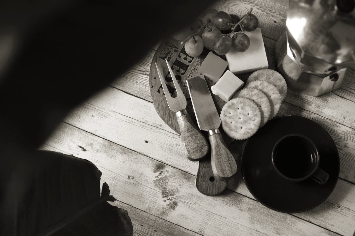 A wooden serving board set laid out with cheese knives and small bowls