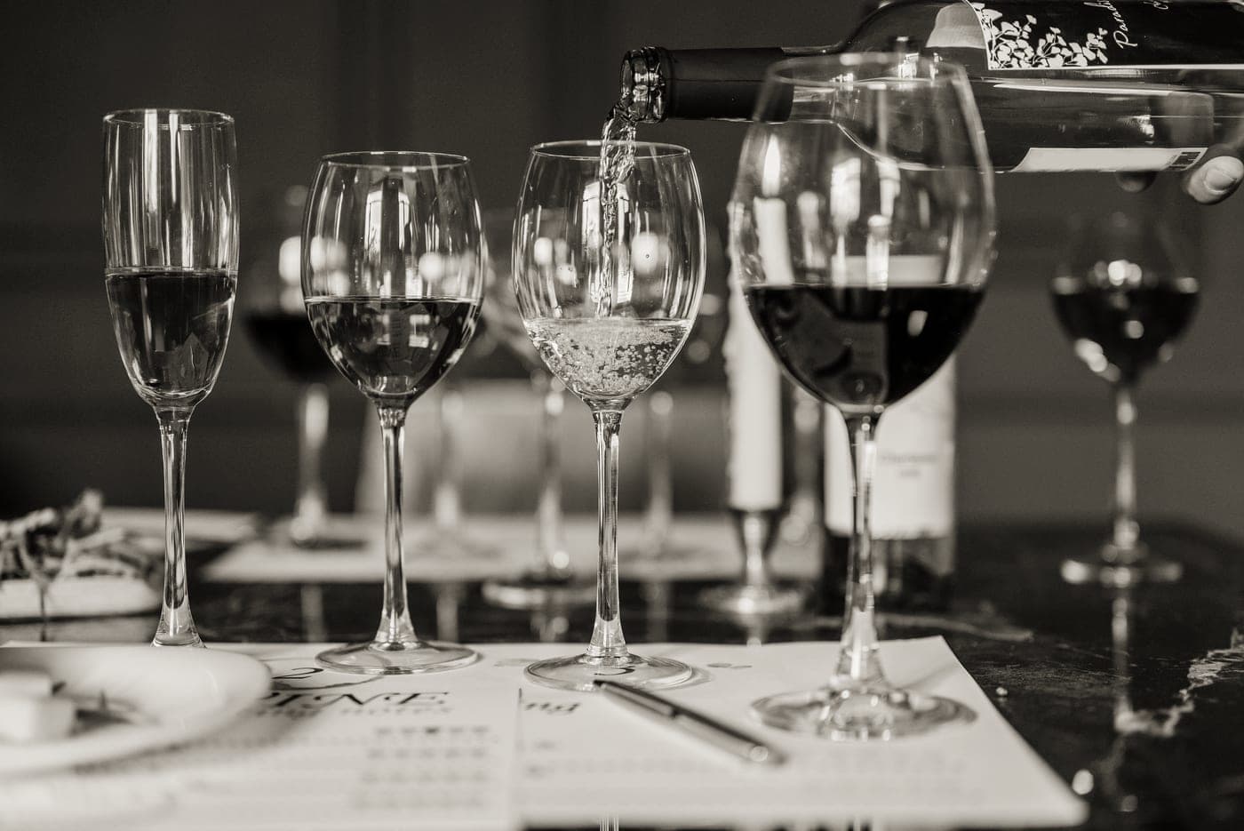 Wine being poured into glasses at a dinner party table